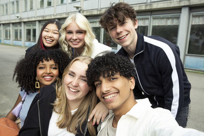 Portrait of smiling male and female friends against building