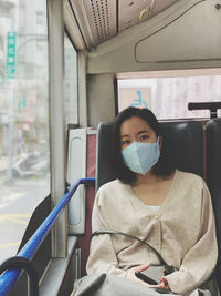 Portrait of woman wearing mask sitting in bus