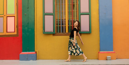 Woman standing against yellow door
