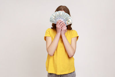 Portrait of young woman standing against white background