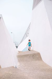 Man standing on umbrella against sky