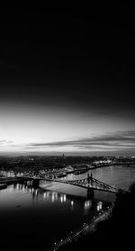 Illuminated bridge over sea against sky at night