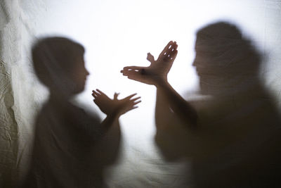 Mother and son playing with shadows behind a bed sheet