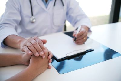 Midsection of doctor consoling patient in hospital