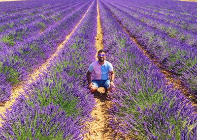 Full length of man crouching amidst lavenders in farm