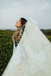 Side view of woman standing on field against sky