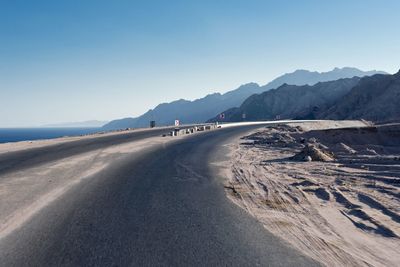 Scenic view of road and mountains against clear sky