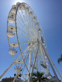 Low angle view of ferris wheel against clear blue sky
