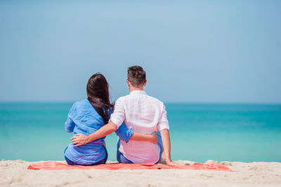 Rear view of friends on beach against sky