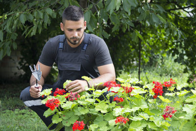 Full length of young man holding flowering plants