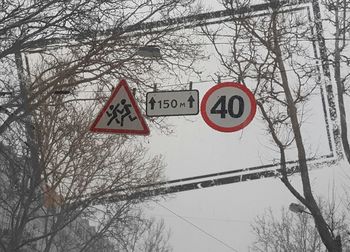 Low angle view of road sign against sky during winter