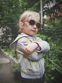 Portrait of cute little girl standing by plants in yard