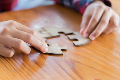 Close-up of person holding jigsaw pieces on table