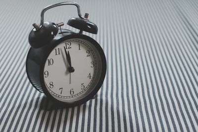 High angle view of alarm clock on striped tablecloth