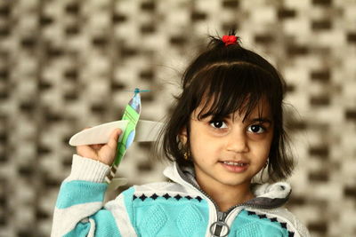 Close-up portrait of girl holding toy airplane