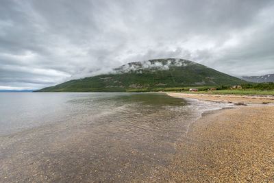 Scenic view of mountain by sea against sky