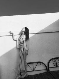 Young woman standing by wall outdoors