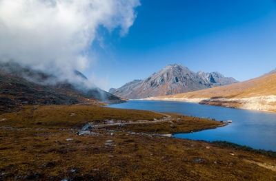 Scenic view of lake by mountains against sky