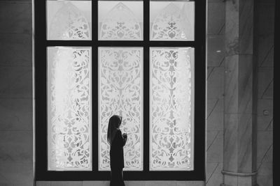 Rear view of woman standing by window