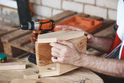 A man collects birdhouse from wooden blanks for a birdhouse. hands close up. diy concept.