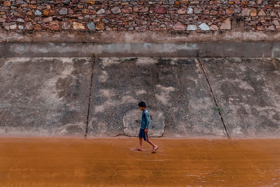 Full length of man walking against wall