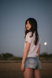 An asian girl on a beach. hair, jeans, sunset