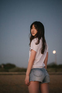 Beautiful woman standing on field against sky