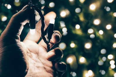 Close-up of hand holding illuminated christmas tree at night