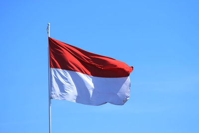 Low angle view of flag against clear blue sky