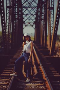 Full length of woman sitting on railroad track