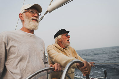 Friends sailing boat on sea against clear sky