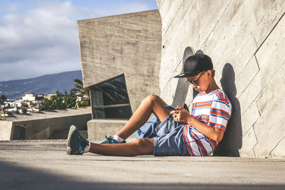 Full length of man sitting on mobile phone