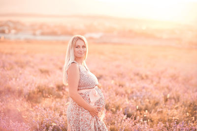 Smiling pregnant woman standing on field