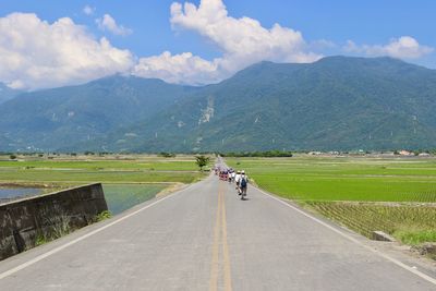 People riding motorcycle on road against sky