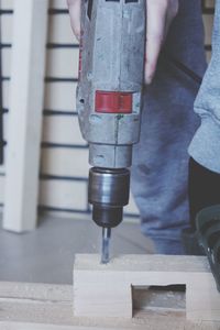 Low section of man drilling wood in workshop