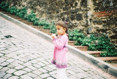 Cute girl looking away while standing on footpath