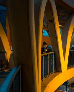 Young woman using mobile phone while standing on footbridge