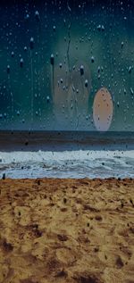 Wet sand on beach against sky during rainy season