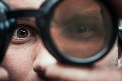 Close-up portrait of man looking through eye test equipment