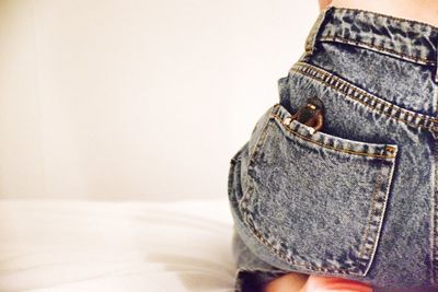 Midsection of woman with figurine in pocket sitting on bed