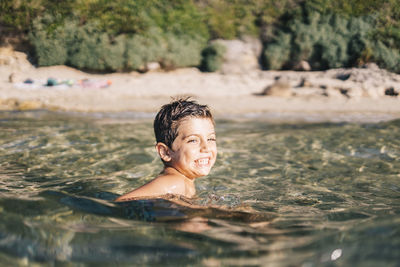 Happy boy looking away while swimming in sea