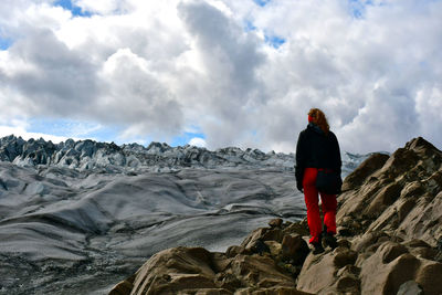 Rear view of woman standing on rock looking at the glacier