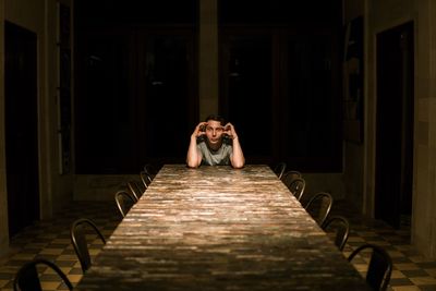 Portrait of man sitting on table in dark room