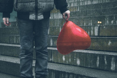 Low section of man with umbrella standing on rainy day