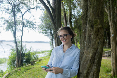 Young woman using a smartphone at day time at a green park. mobile phone, technology,