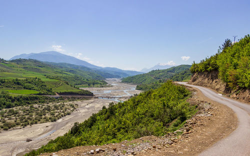 Scenic view of road by mountains against sky