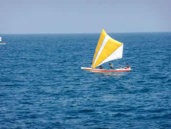 Sailboat sailing in sea against clear sky