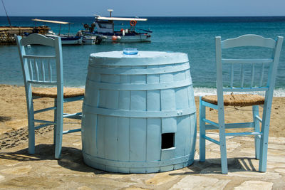 Chairs on beach by sea against sky
