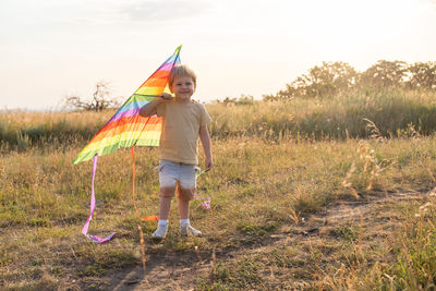 Rear view of woman with umbrella standing on field against sky