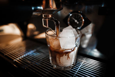 Close-up of coffee pouring in drink glass at cafe